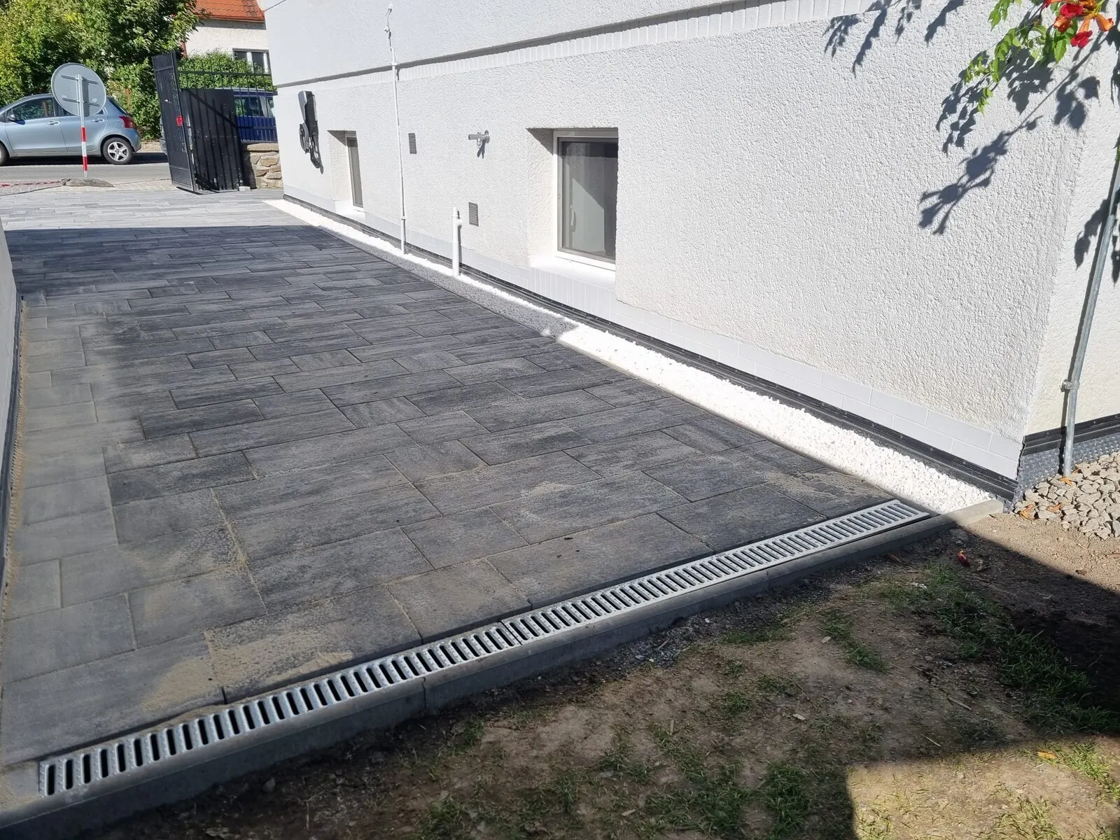 Hotová dlážděná plocha u bílé haly s odvodňovacím žlabem po obvodu